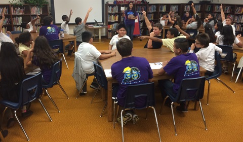 Classroom setting with children raising their hands